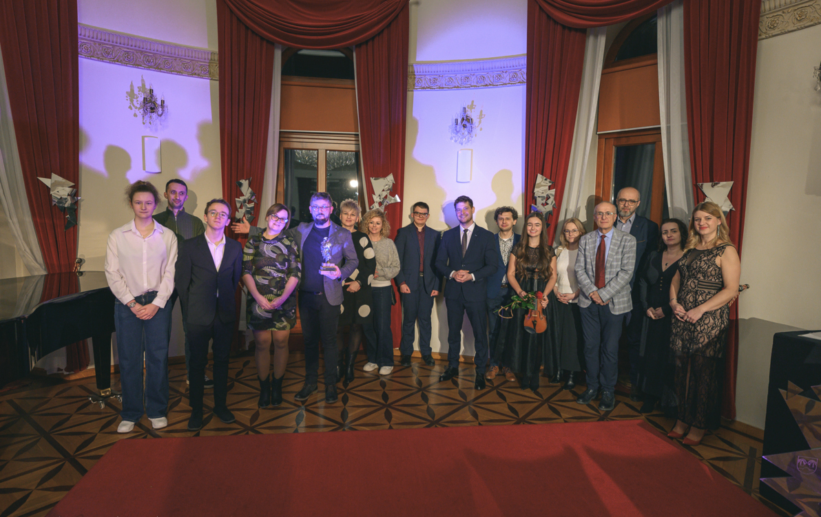 grupa ludzi w sali koncertowej stoi na scenie