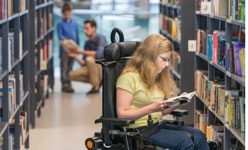 dziewczyna na wózku inwalidzkim czytająca książkę w bibliotece